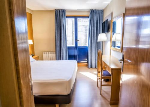 a hotel room with a bed and a desk and a window at Hotel Alda Castelao in Vilagarcia de Arousa