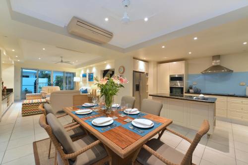 a kitchen and living room with a wooden table and chairs at Reef Villa Port Douglas in Port Douglas