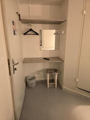 a small bathroom with a mirror and a stool at Brit Hotel Essentiel Poitiers Gare du Futuroscope in Jaunay-Marigny
