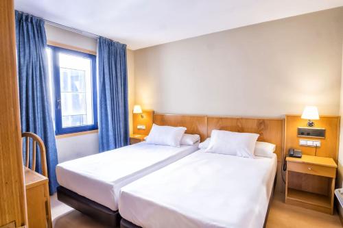 a bedroom with a large white bed with a window at Hotel Alda Castelao in Vilagarcia de Arousa
