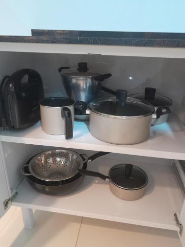 a shelf with several pots and pans on it at FLAT a 2min do relogio da flores com ar condicionado in Garanhuns