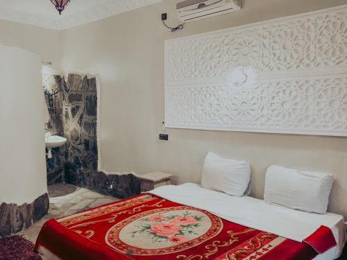 a bedroom with a bed with a red blanket on it at Hamada Du Draa in Mhamid