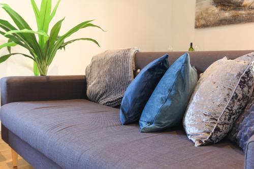 a couch with blue pillows on it in a living room at Elegant 2bd Flat in Brighton Marina - Free Parking in Brighton & Hove