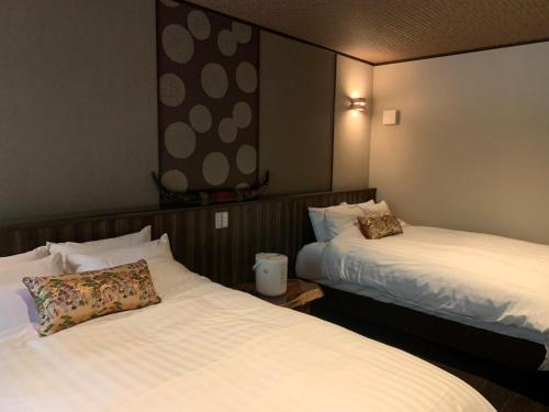 two beds in a hotel room with white sheets at Shiseki Ryokan Kagetsu Taishoukan - Vacation STAY 48535v in Takeo