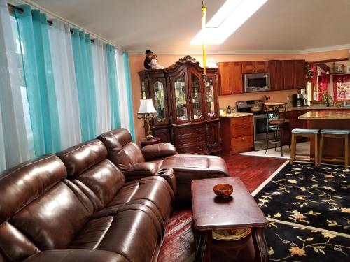 a living room with a leather couch and a kitchen at Fully renovated 4 bd with 2 master suits, 3 bth home in centralized location in Keaau