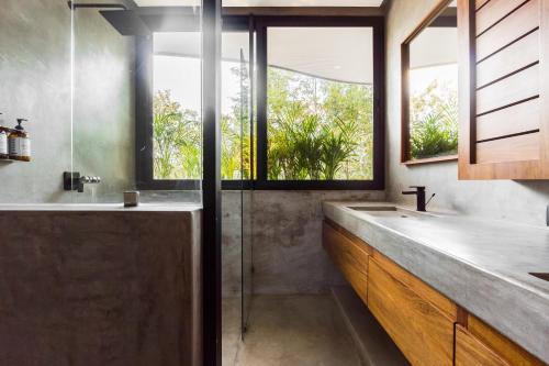 a bathroom with a tub and a sink and windows at Luxury 4BR Eco Villa 10ppl Outdoor Pizza Oven - Private Pool & Jacuzzi in Tulum