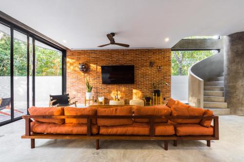 a living room with a brown couch in front of a brick wall at Luxury 4BR Eco Villa 10ppl Outdoor Pizza Oven - Private Pool & Jacuzzi in Tulum