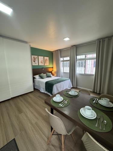 a hotel room with a bed and a table and chairs at Loft Studio no Kobrasol in São José