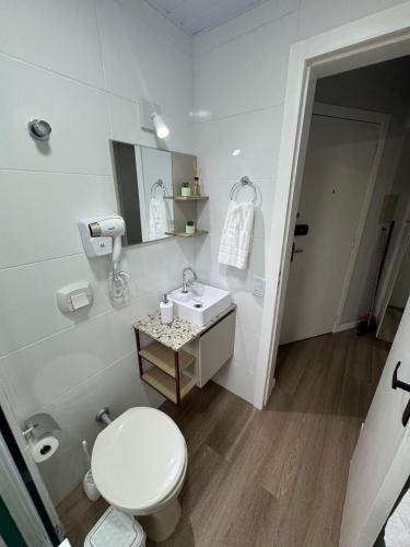 a white bathroom with a toilet and a sink at Loft Studio no Kobrasol in São José
