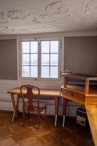 a dining room table with a chair and two windows at Haus zum Schiff in Ermatingen