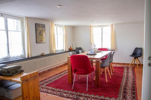 a dining room with a table and red chairs at Haus zum Schiff in Ermatingen