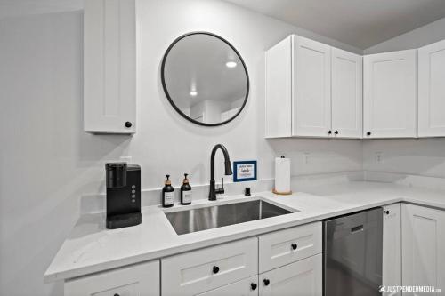 a white kitchen with a sink and a mirror at Cozy Eagle River Retreat in Eagle River