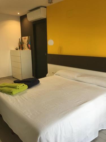 a bedroom with a white bed and a yellow wall at Atico Pelayo in Castellón de la Plana