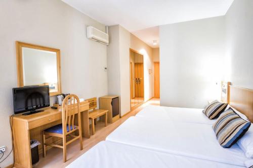 a bedroom with two beds and a desk and a mirror at Hotel Alda Castelao in Vilagarcia de Arousa
