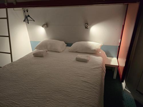 a bed in a room with two pillows on it at Brit Hotel Essentiel Poitiers Gare du Futuroscope in Jaunay-Marigny