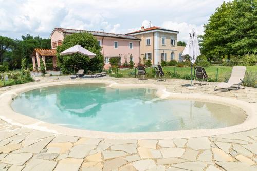 a swimming pool with chairs and a house in the background at Villa Donnola: casa Rosmarino in Fucecchio