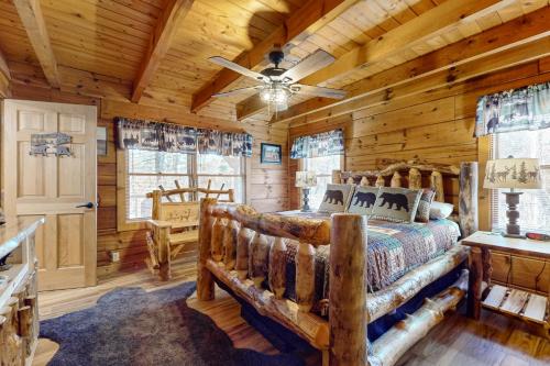 Un dormitorio tipo cabaña de madera con una cama y un ventilador de techo. en Bears, Bees and Trees, en Sevierville