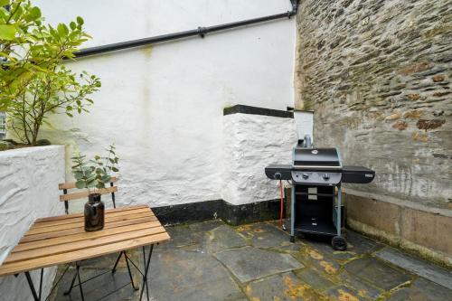 a grill and a wooden bench in a courtyard at Moll's Yard in Port Isaac