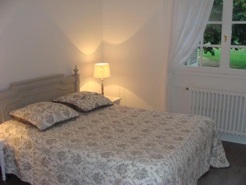 a bedroom with a bed with a lamp and a window at La Petite Trolière in Orval