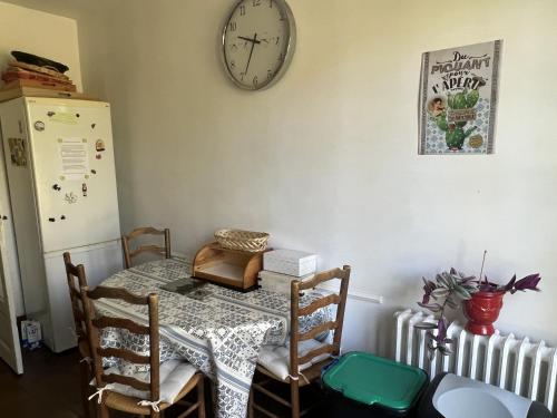 a dining room with a table and a clock on the wall at La Petite Trolière in Orval