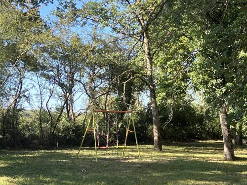 a swing set in the middle of a park with trees at La Petite Trolière in Orval