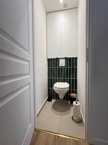 a bathroom with a toilet and a black tiled wall at KB 21 - Metro 7 - AC - Free Parking - 4 pers in Le Kremlin-Bicêtre