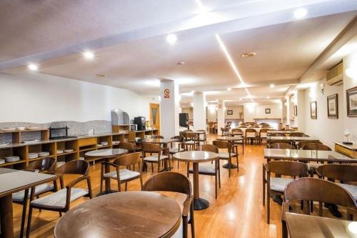 a dining room with tables and chairs and shelves at Hotel Alda Castelao in Vilagarcia de Arousa