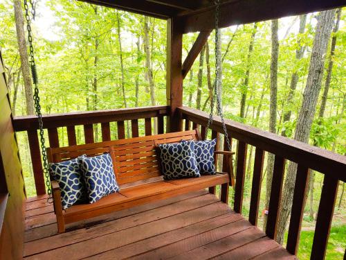 a wooden bench on a porch with pillows on it at Trailseeker Cabin w King Bed Hot Tub at Red River Gorge Natural Bridge in Stanton