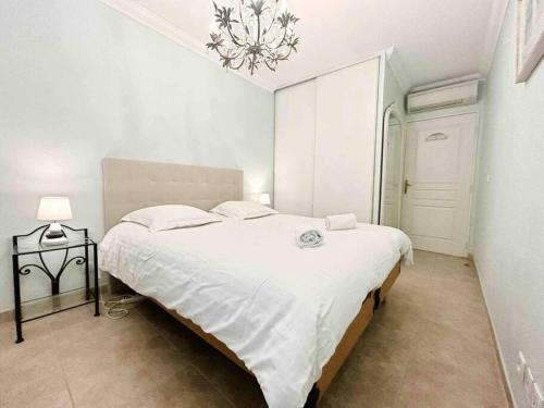 - une chambre blanche avec un grand lit et un lustre dans l'établissement Le Square Pauline, Apt 4 Prs, Jardin, 300m Mer, à Antibes