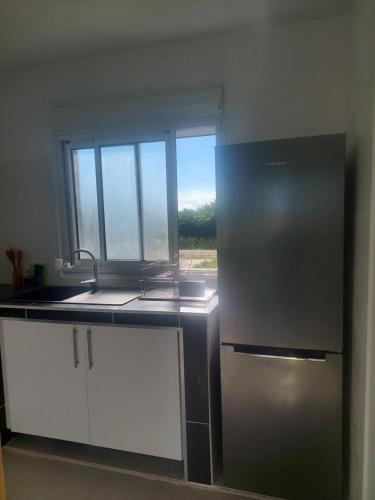 a kitchen with a stainless steel refrigerator and a window at Gaby villa in Capesterre