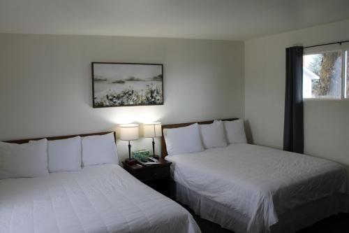 two beds in a room with white walls and a window at Sprague Motel in Sprague