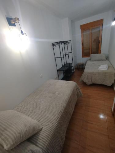 a room with two beds and a light on the wall at Los tres balcones in Caravaca de la Cruz