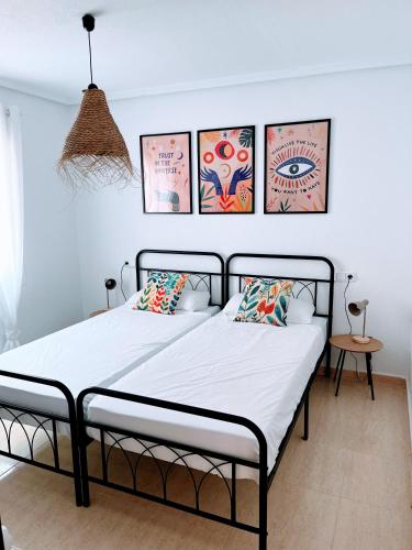 1 dormitorio con 1 cama con 4 cuadros en la pared en Casa Vinna, en Mazarrón