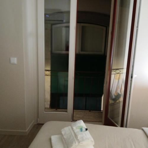 a room with a bed and a mirror with towels at CasAmalia 54 in Viana do Castelo