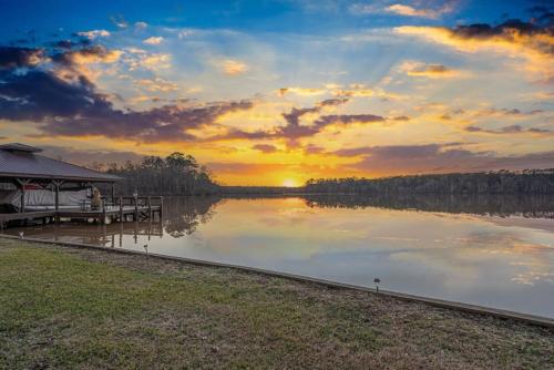 a dock on a lake with a sunset in the background at Ultimate Family Fun Lakehouse with pool and dock in Eatonton