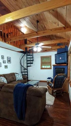 a living room with a couch and a staircase at Trailseeker Cabin w King Bed Hot Tub at Red River Gorge Natural Bridge in Stanton