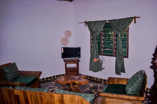 a living room with chairs and a table and a television at Jaffrane in Ukunda