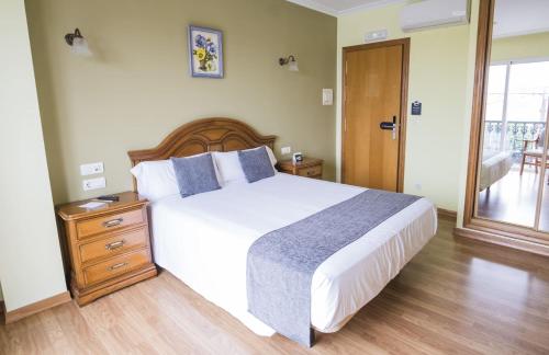 a bedroom with a large bed with a wooden headboard at Alda Alpina in Villanueva de Arosa