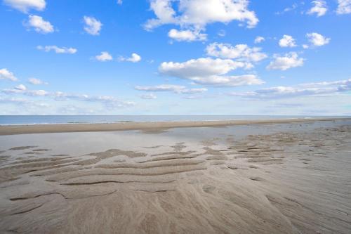 a sandy beach with a blue sky and clouds at Tybee Turtle Time Condo in Tybee Island