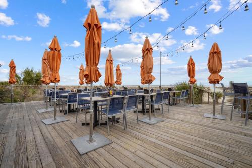 a patio with tables and umbrellas on a deck at Tybee Turtle Time Condo in Tybee Island