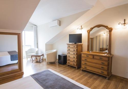 a bedroom with a bed and a dresser with a mirror at Alda Alpina in Villanueva de Arosa