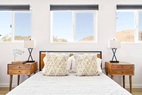 a white bedroom with a large bed with two night stands at Desert Escape Climbing Wall, Hammocks & Hot Tub15 Min to Joshua Tree Park in Joshua Tree