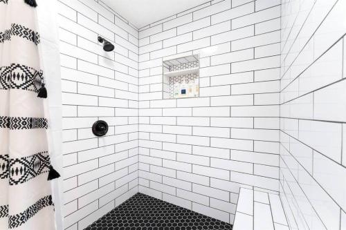 a white tiled shower with a black and white tile floor at Desert Escape Climbing Wall, Hammocks & Hot Tub15 Min to Joshua Tree Park in Joshua Tree