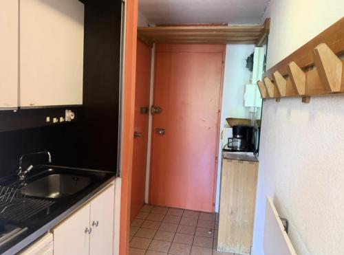 - une cuisine avec une porte rouge et un évier dans l'établissement Résidence Lac Du Lou - Studio 4 pers ski aux pieds au coeur des Menuires MAE-5054, aux Menuires