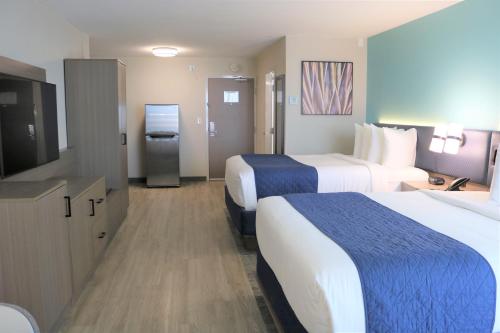 a hotel room with two beds and a flat screen tv at Best Western Aku Tiki Inn in Daytona Beach