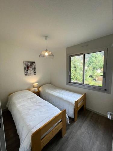 deux lits dans une chambre avec une fenêtre dans l'établissement Résidence Couderes - APPARTEMENT 4 PERSONNES A DEUX PAS DU CENTRE MAE-4764, à Saint-Lary-Soulan