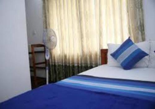 a bedroom with a bed with a blue pillow and a window at Ivory Safari Lodge in Udawalawe