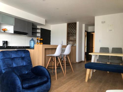 a living room with two chairs and a kitchen at Apartamento Maranda in Ipiales