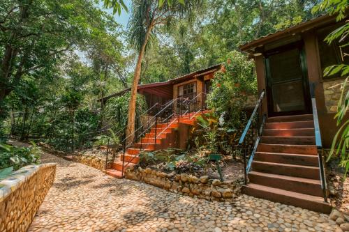 a house with an orange staircase next to a building at Sweet Songs Jungle Lodge in San Ignacio