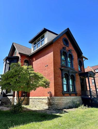 a red brick house with a tree in front of it at King Bed Suite-Free Parking-Prime Location in Detroit